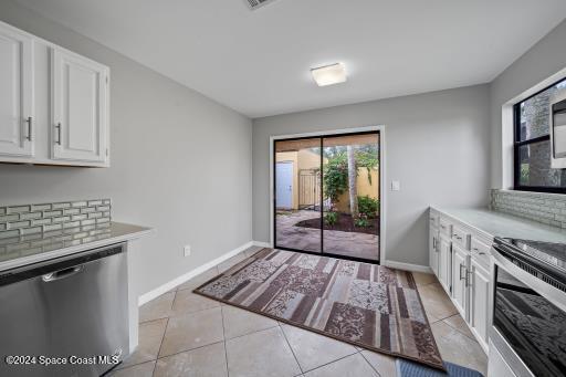 kitchen with decorative backsplash, light tile patterned flooring, white cabinetry, and appliances with stainless steel finishes