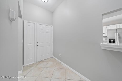 hallway with light tile patterned floors and vaulted ceiling