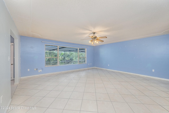 tiled empty room featuring ceiling fan and a textured ceiling