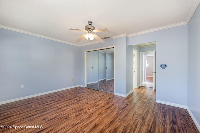 unfurnished bedroom featuring ceiling fan, dark hardwood / wood-style floors, ornamental molding, and a closet