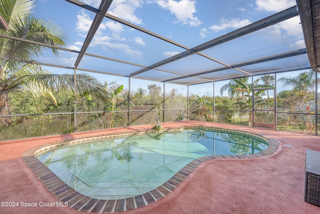 view of pool with glass enclosure and a patio