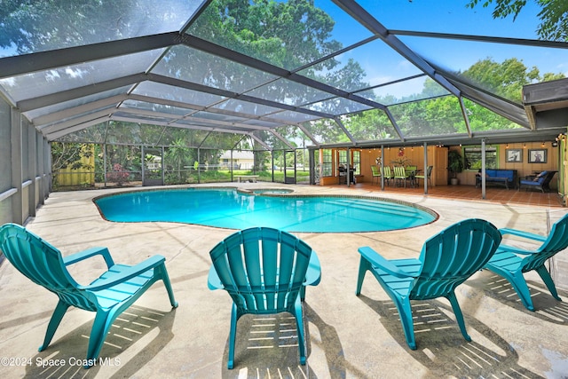 view of pool with outdoor lounge area, a patio, and a lanai