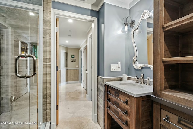 bathroom featuring vanity, ornamental molding, and a shower with door