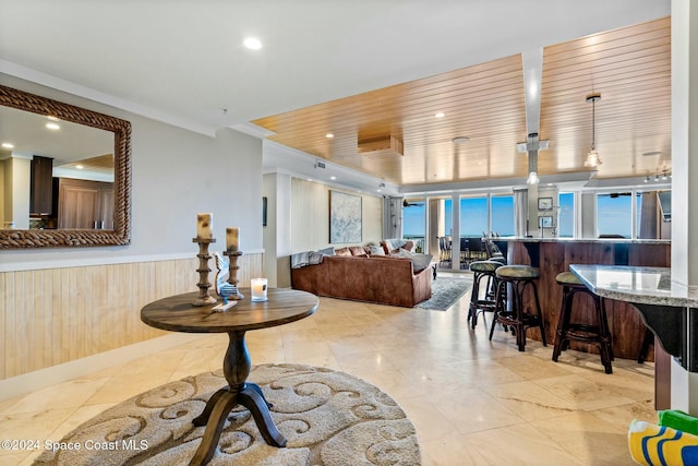 living room with crown molding and wood walls