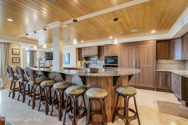 kitchen featuring light stone countertops, tasteful backsplash, a kitchen breakfast bar, decorative light fixtures, and wood ceiling