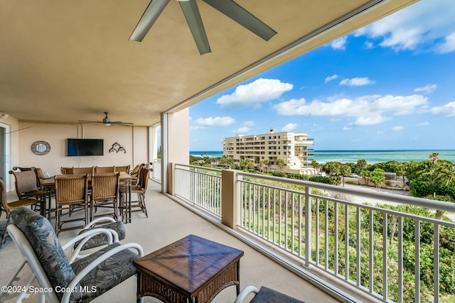 balcony with ceiling fan and a water view