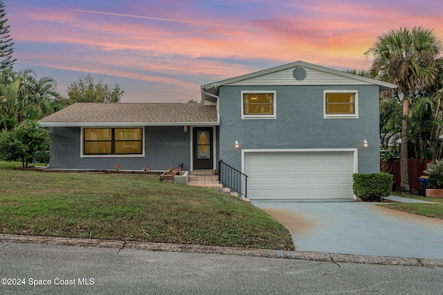 split level home featuring a garage and a yard