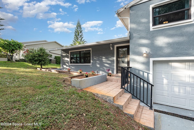 view of exterior entry featuring a garage and a yard