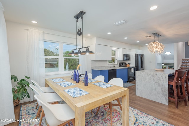 dining area featuring an inviting chandelier, sink, and light hardwood / wood-style flooring