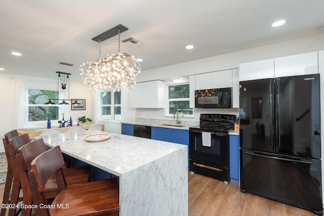 kitchen with white cabinetry, a center island, sink, pendant lighting, and black appliances