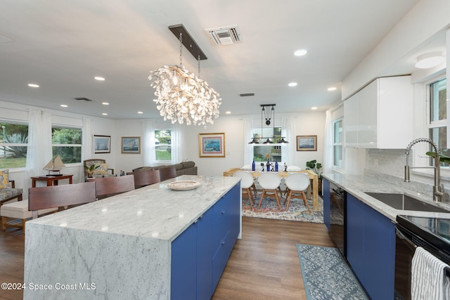 kitchen with dark hardwood / wood-style floors, black dishwasher, blue cabinetry, decorative light fixtures, and a kitchen island