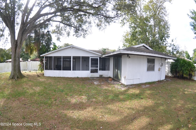 back of house with a sunroom and a lawn