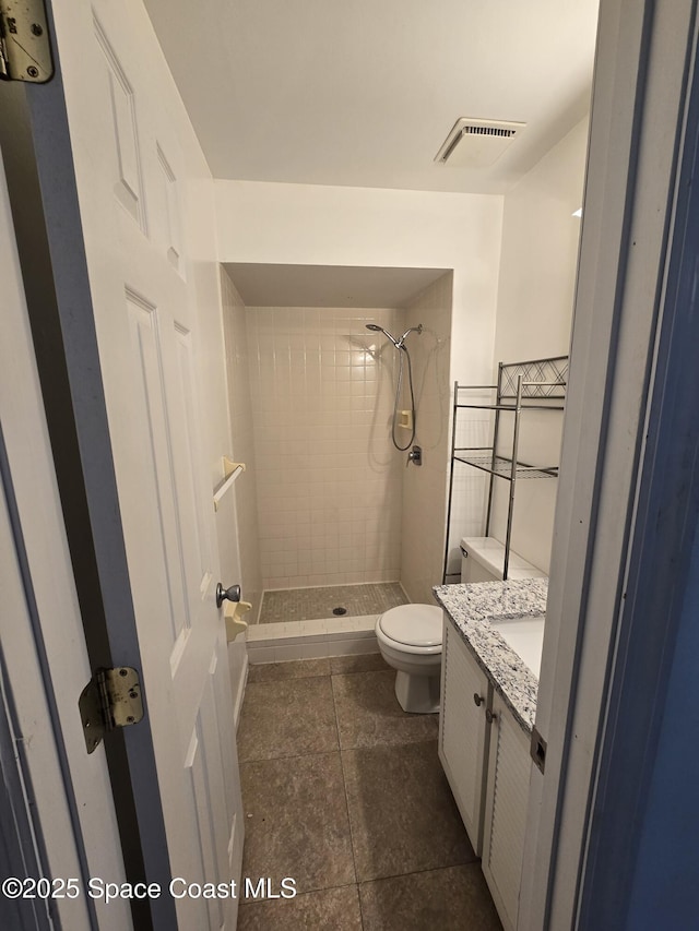 bathroom with vanity, tiled shower, tile patterned floors, and toilet