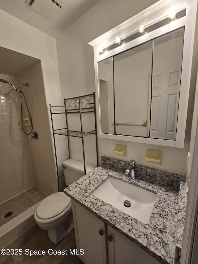 bathroom with vanity, tile patterned flooring, toilet, and tiled shower