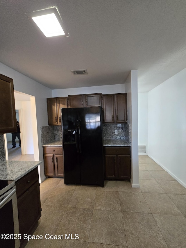 kitchen with tasteful backsplash, light stone counters, dark brown cabinets, and black refrigerator with ice dispenser