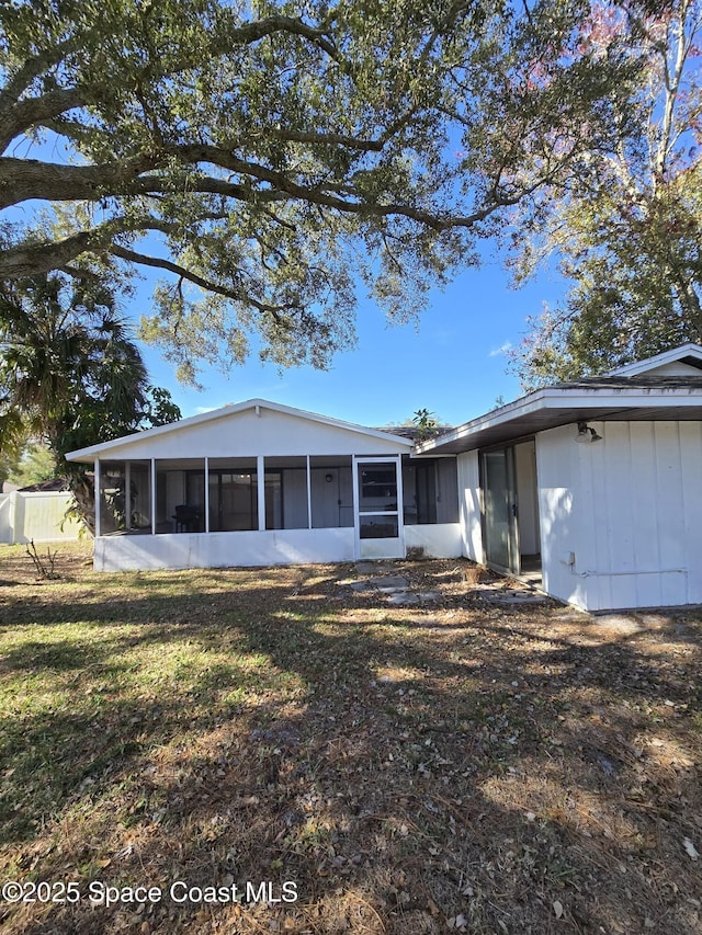 back of house with a sunroom and a yard