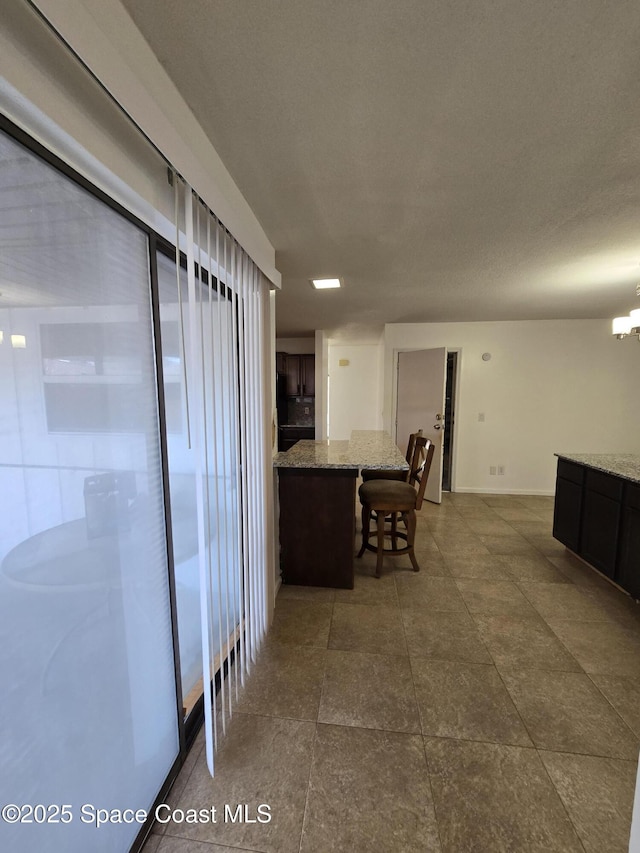 interior space with a breakfast bar, light stone counters, and dark brown cabinetry