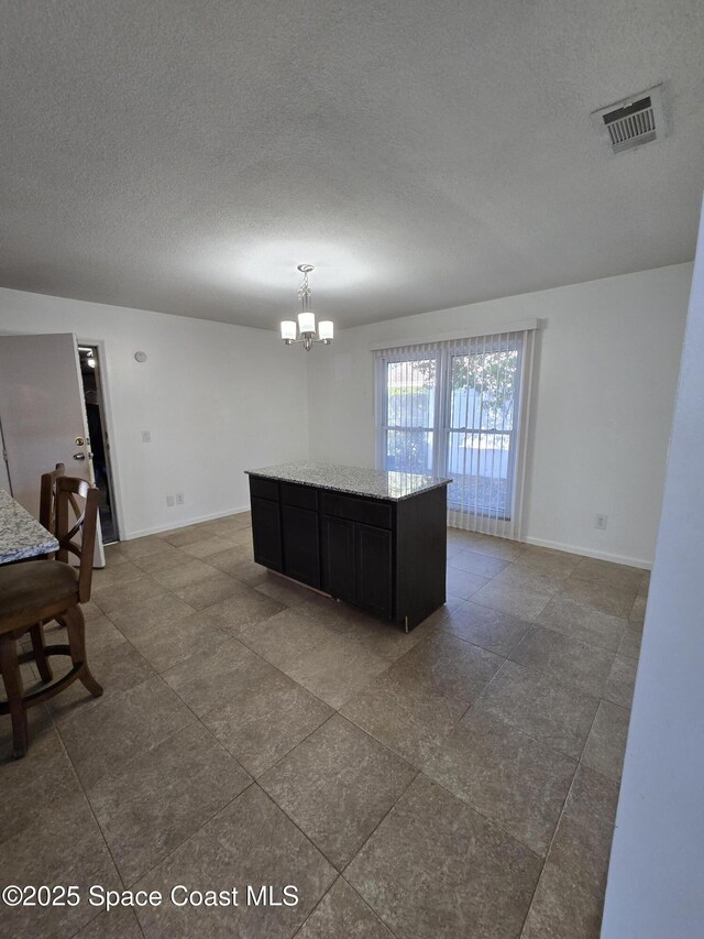 kitchen featuring a center island, a notable chandelier, light stone counters, and decorative light fixtures