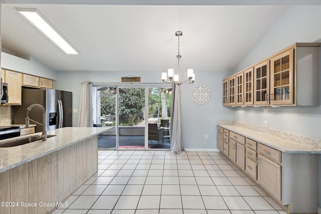 kitchen featuring light stone counters, sink, hanging light fixtures, and vaulted ceiling