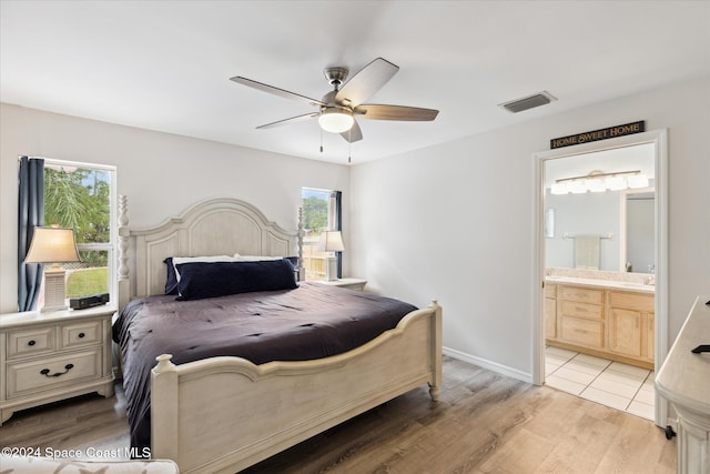 bedroom with ensuite bathroom, ceiling fan, light wood-type flooring, and multiple windows