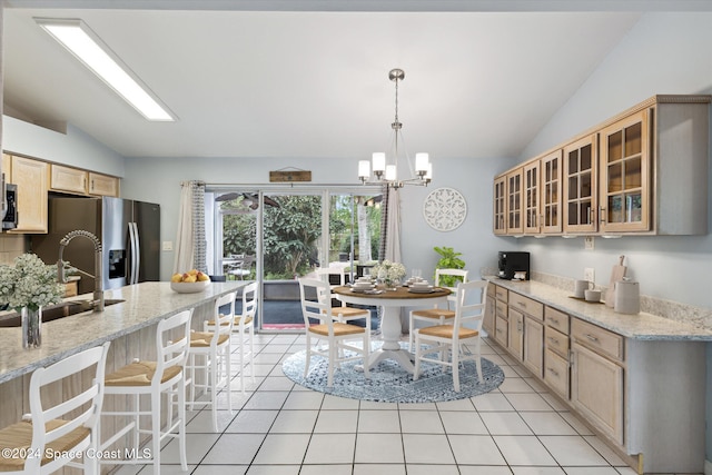 kitchen with light stone countertops, appliances with stainless steel finishes, vaulted ceiling, decorative light fixtures, and a chandelier