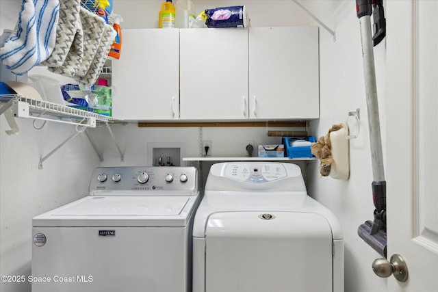 clothes washing area featuring cabinets and separate washer and dryer