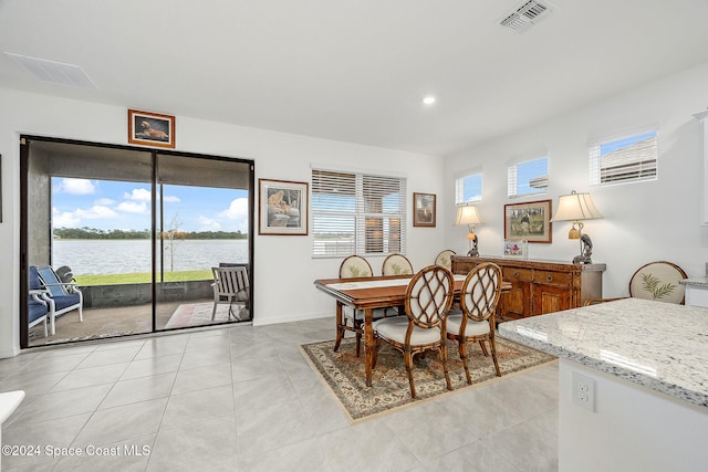 dining room with a water view and light tile patterned floors