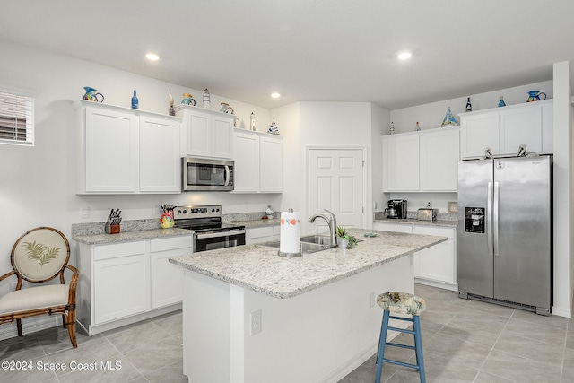 kitchen with white cabinetry, an island with sink, light stone countertops, and appliances with stainless steel finishes