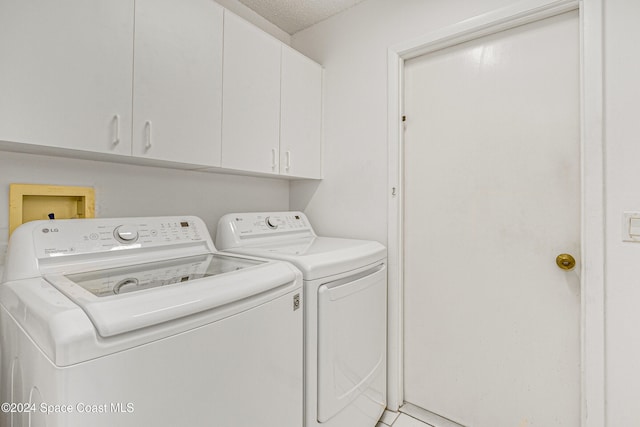 washroom featuring cabinets, independent washer and dryer, a textured ceiling, and tile patterned flooring