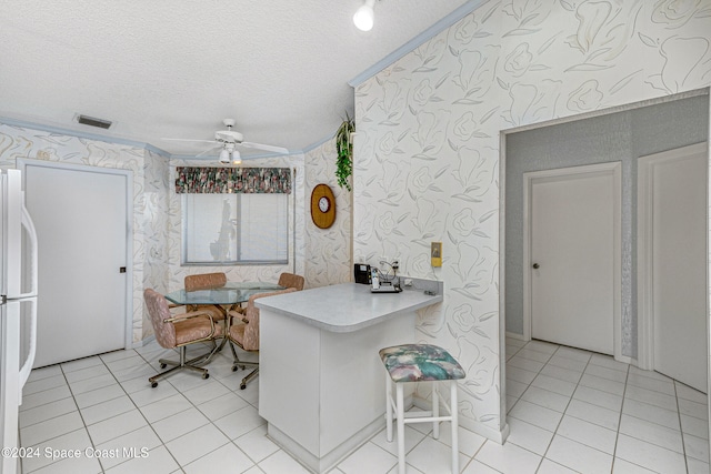 kitchen featuring ceiling fan, light tile patterned floors, white fridge, and a textured ceiling