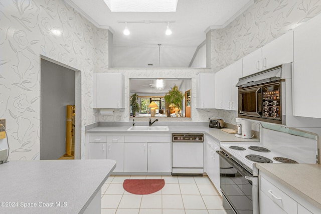 kitchen featuring a skylight, white cabinetry, sink, white appliances, and light tile patterned floors