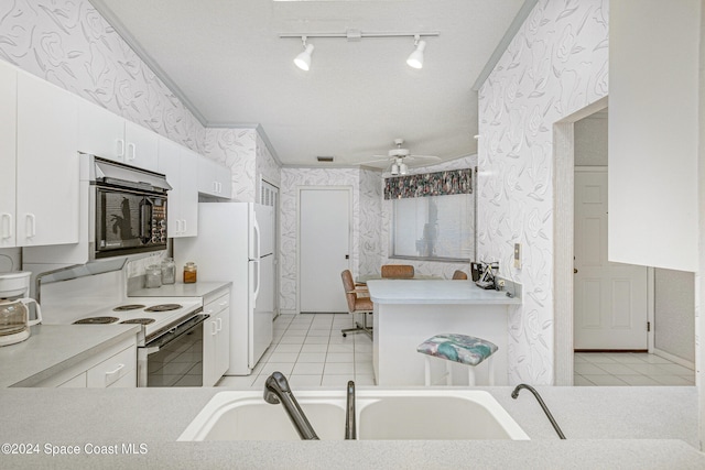 kitchen featuring white appliances, ceiling fan, crown molding, sink, and white cabinets