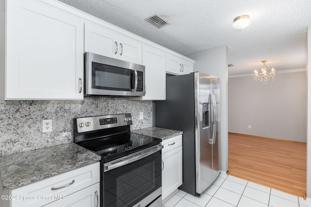 kitchen featuring stainless steel appliances, a notable chandelier, decorative backsplash, white cabinets, and light wood-type flooring