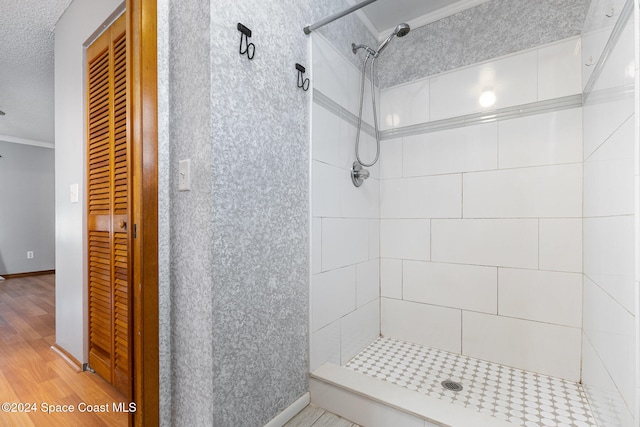 bathroom with tiled shower, wood-type flooring, a textured ceiling, and ornamental molding