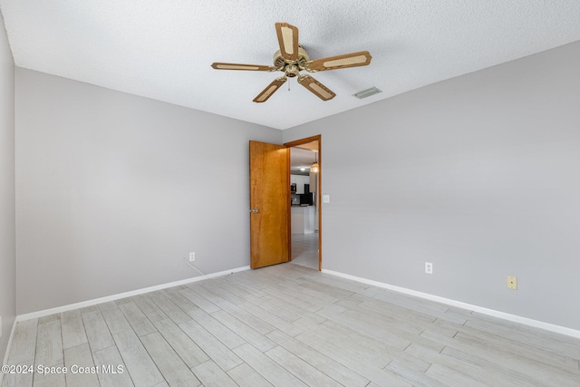 unfurnished room with a textured ceiling, light hardwood / wood-style flooring, and ceiling fan