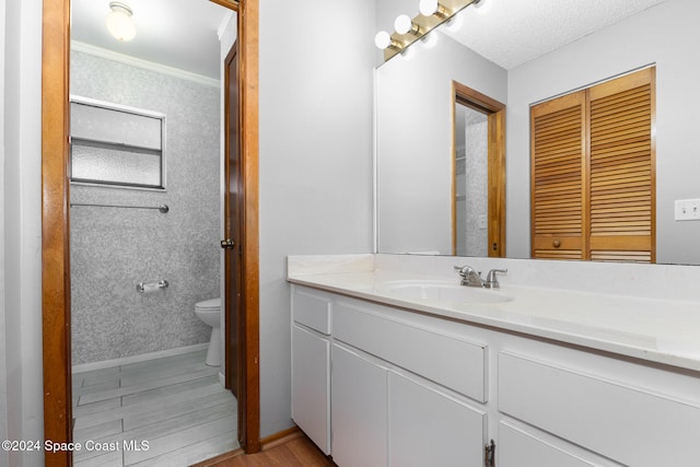 bathroom with crown molding, vanity, wood-type flooring, and toilet