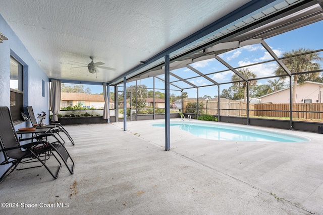 view of pool featuring glass enclosure, ceiling fan, and a patio area