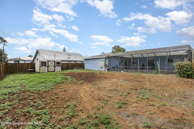 rear view of property with glass enclosure and a shed