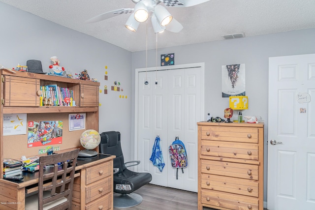 office with ceiling fan, light wood-type flooring, and a textured ceiling