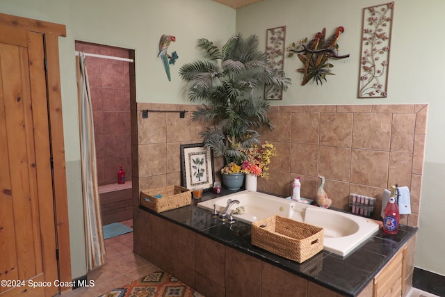 bathroom with tile patterned floors, a relaxing tiled tub, and tile walls