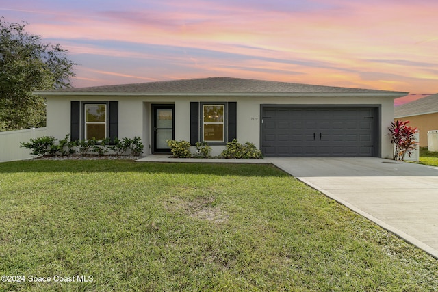 ranch-style home featuring a garage and a yard