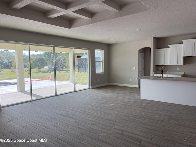 unfurnished living room with hardwood / wood-style floors, sink, and a textured ceiling