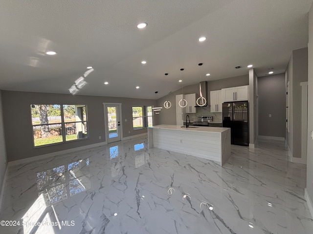 kitchen with pendant lighting, black refrigerator with ice dispenser, wall chimney exhaust hood, an island with sink, and white cabinetry