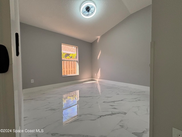 empty room with a textured ceiling and vaulted ceiling