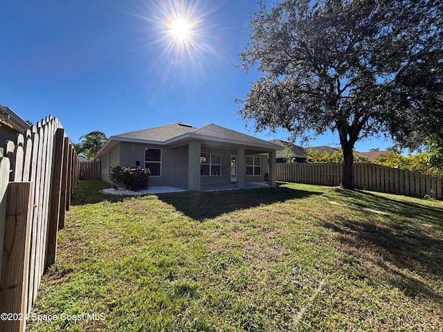 back of property with a yard and a patio