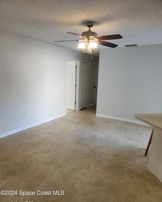 unfurnished room with ceiling fan and a textured ceiling