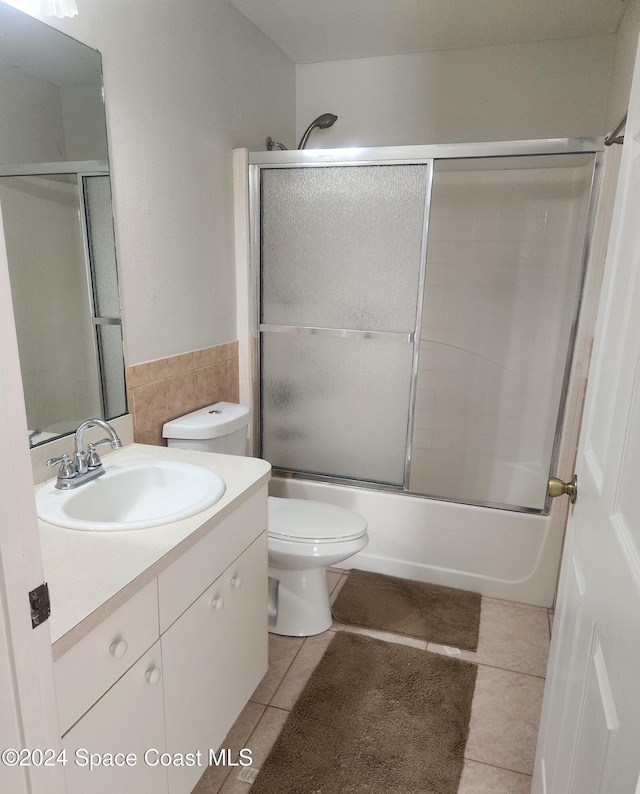 full bathroom with tile patterned floors, toilet, vanity, and combined bath / shower with glass door