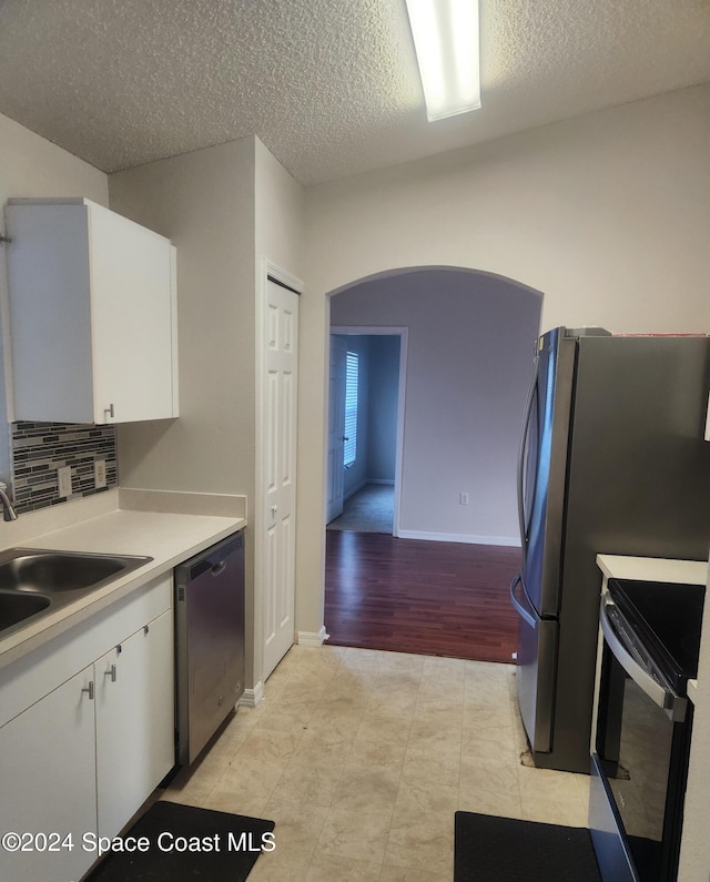 kitchen with appliances with stainless steel finishes, light hardwood / wood-style flooring, white cabinetry, and sink