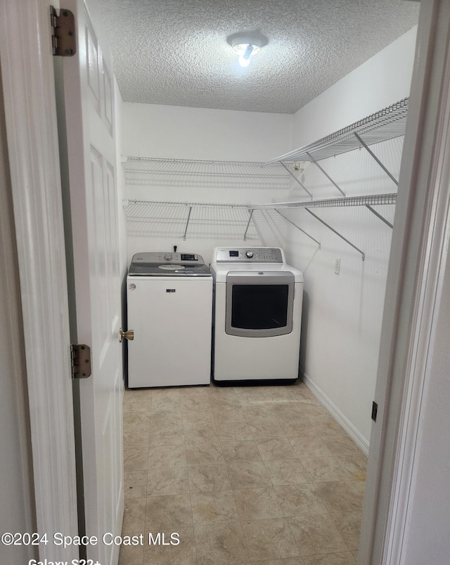 clothes washing area featuring separate washer and dryer and a textured ceiling