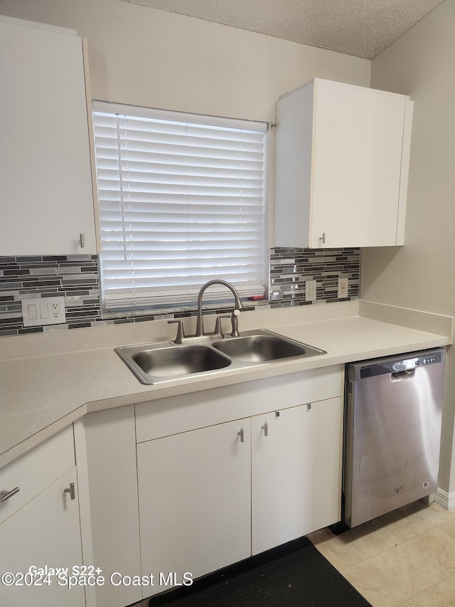 kitchen featuring white cabinetry, sink, stainless steel dishwasher, backsplash, and a textured ceiling